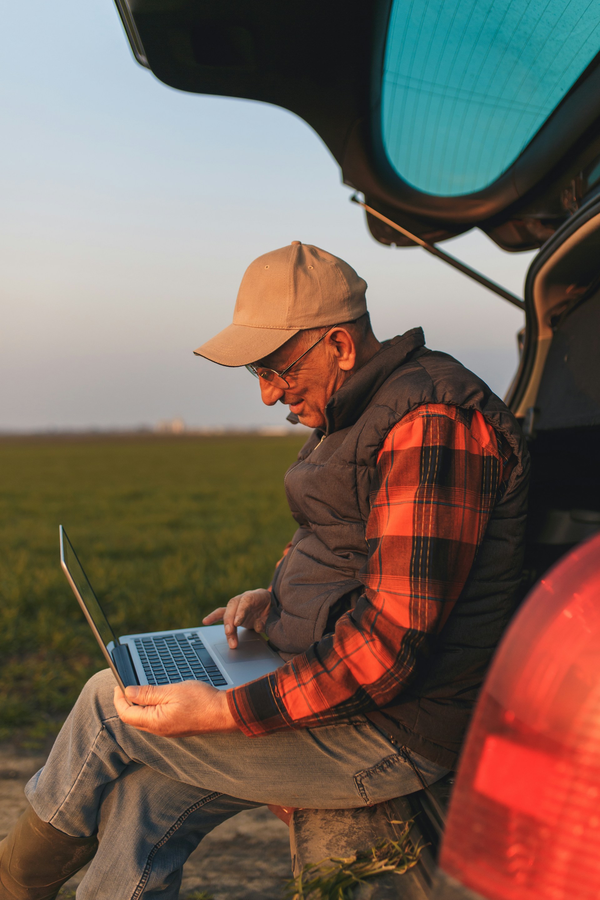 Farmer studying financial reports at desk with field view